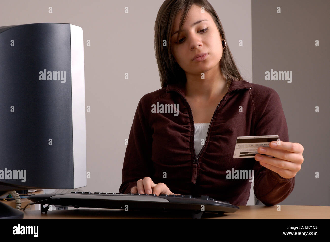 Eine junge Frau macht eine Geldkarte oder Kreditkarte Kauf von ihrem Computer zu Hause. Stockfoto
