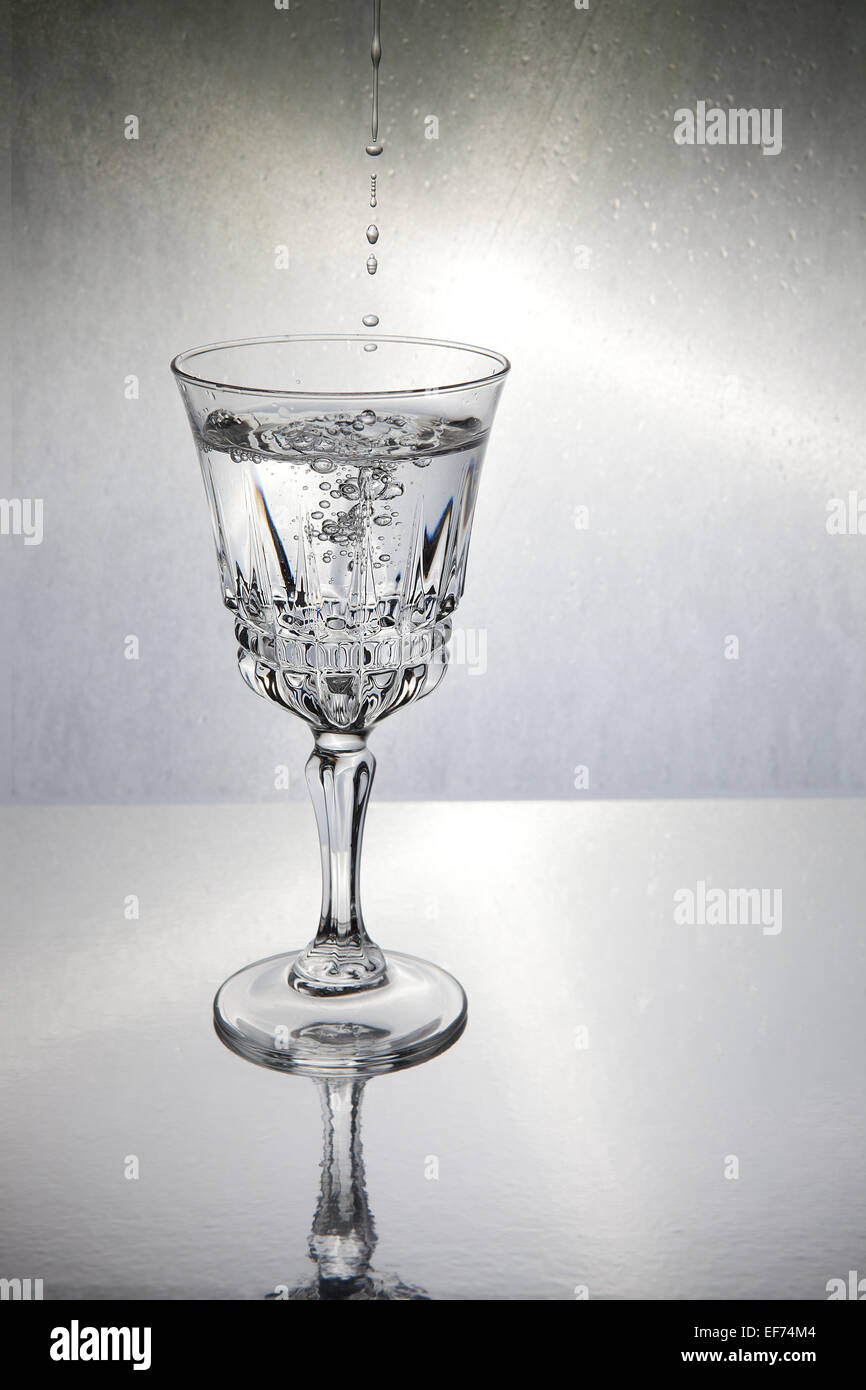 Einige Tropfen in ein Glas mit Wasser gefüllt Stockfoto