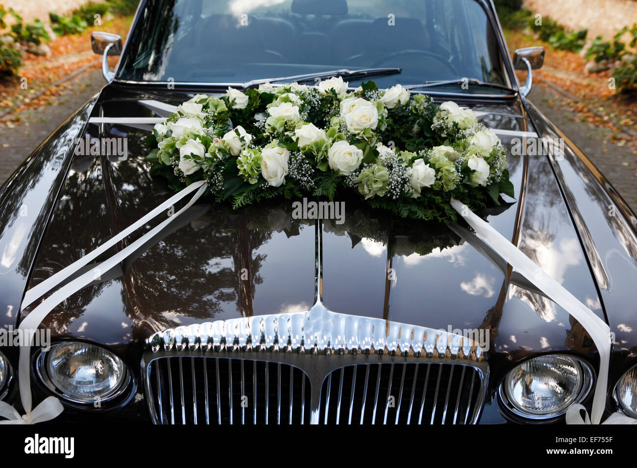 ein schwarzes Hochzeitsauto mit Blumenschmuck auf der Motorhaube