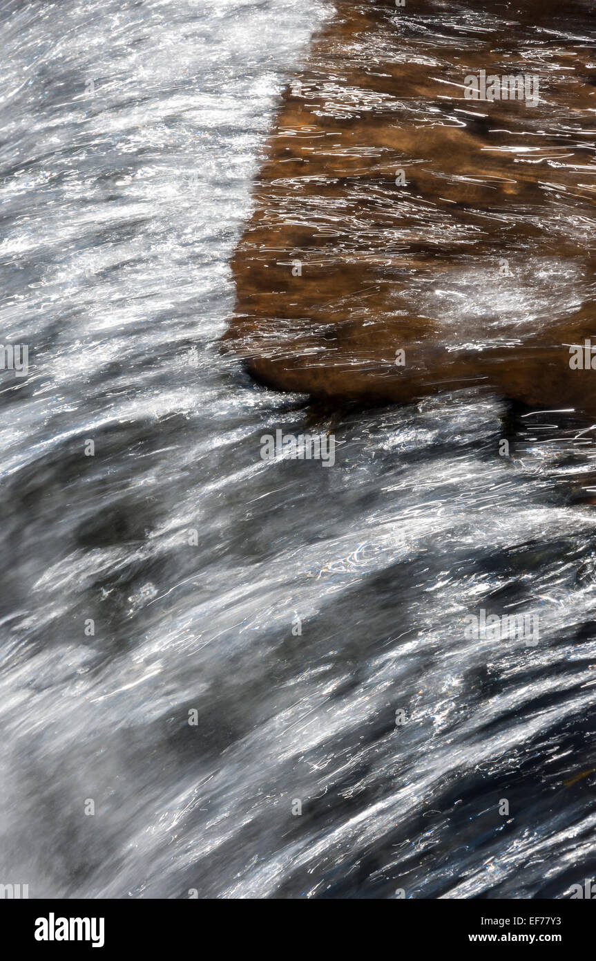 Klares Wasser fließt über Fels am Fairbrook im Peak District an einem sonnigen Frühlingstag. Ein abstraktes Bild von fließendem Wasser. Stockfoto