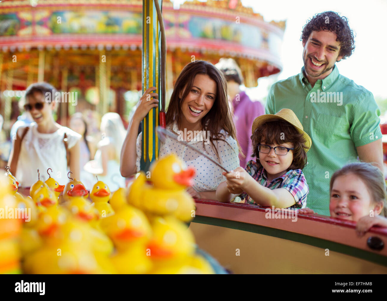Eltern mit zwei Kindern Spaß mit Angelspiel im Vergnügungspark Stockfoto