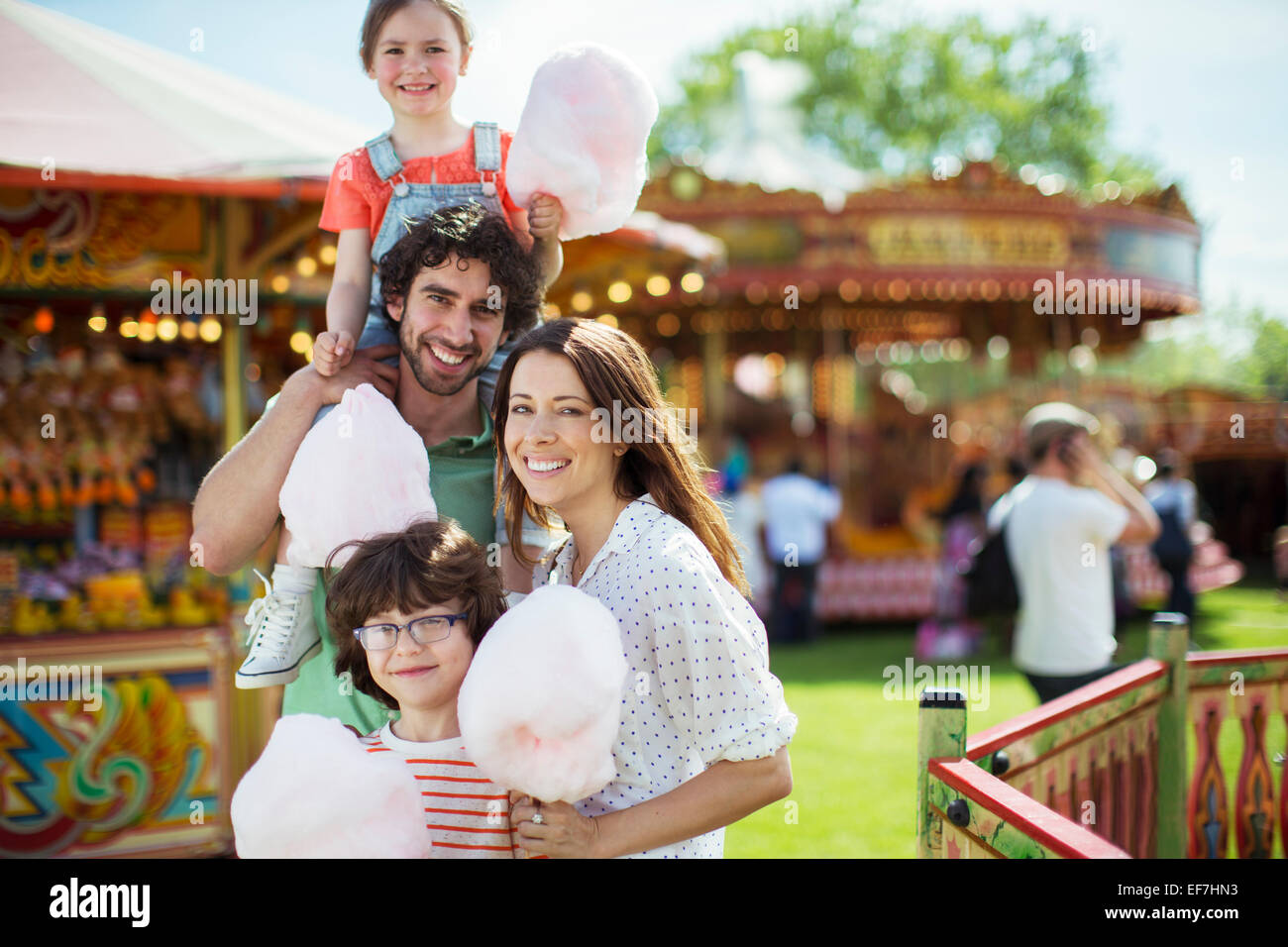 Porträt von fröhlichen Familienholding rosa Zuckerwatte im Vergnügungspark Stockfoto