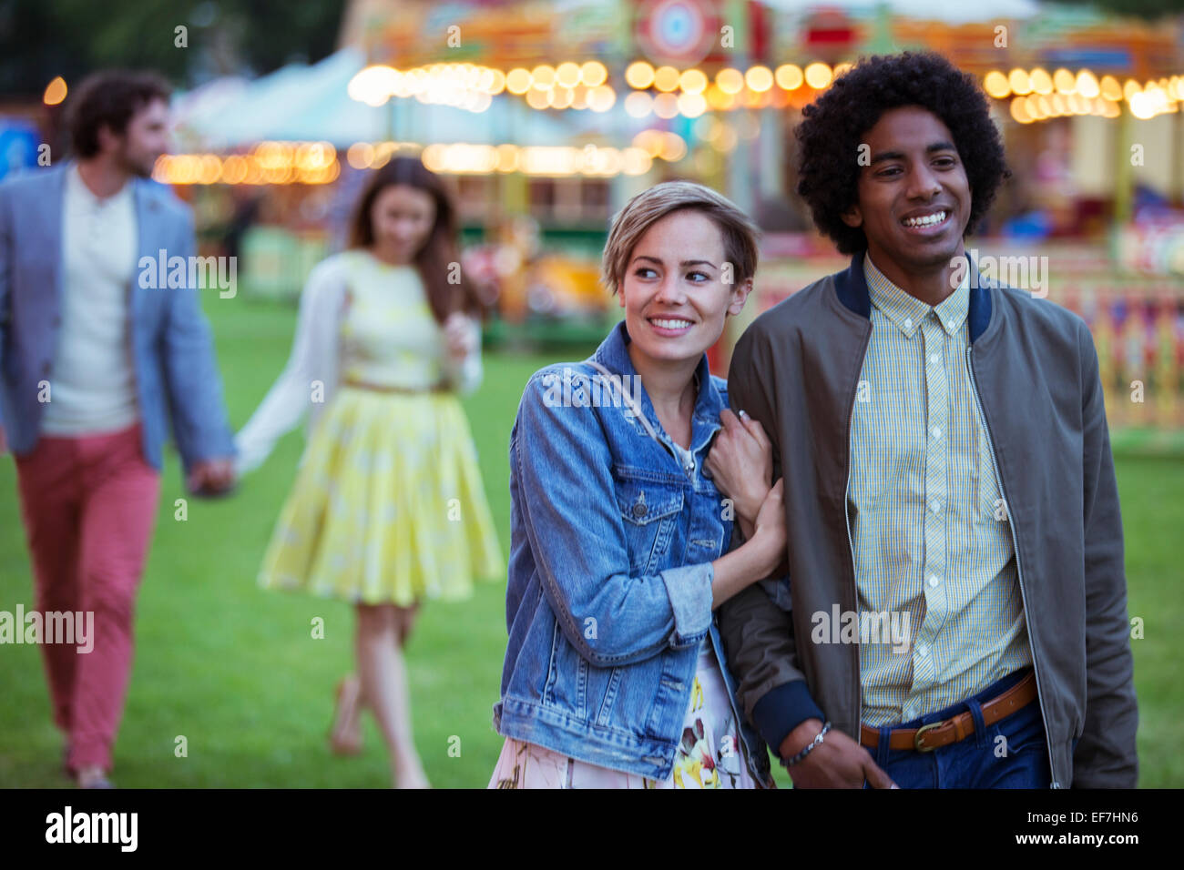 Junge gemischtrassige paar Lächeln während des Gehens im Vergnügungspark Stockfoto