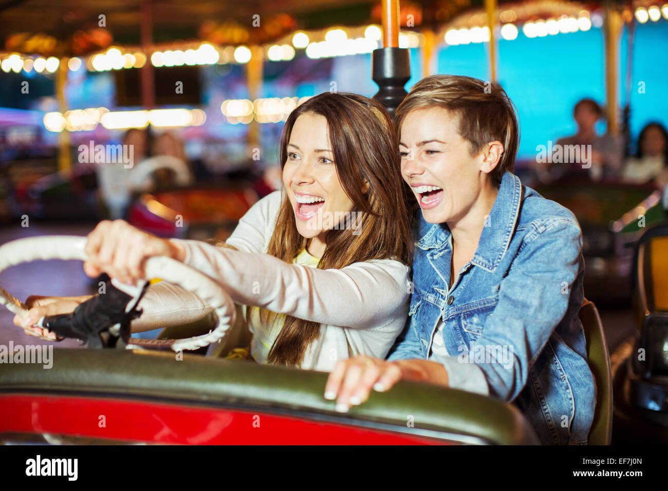Zwei fröhliche Frauen auf Autoscooter fahren im Freizeitpark Stockfoto