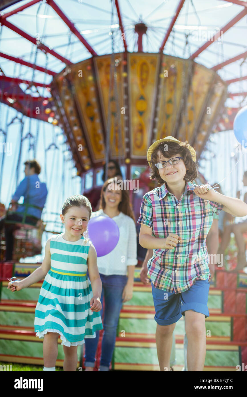 Kinder laufen vor Karussell, Mutter, ihnen zu folgen Stockfoto