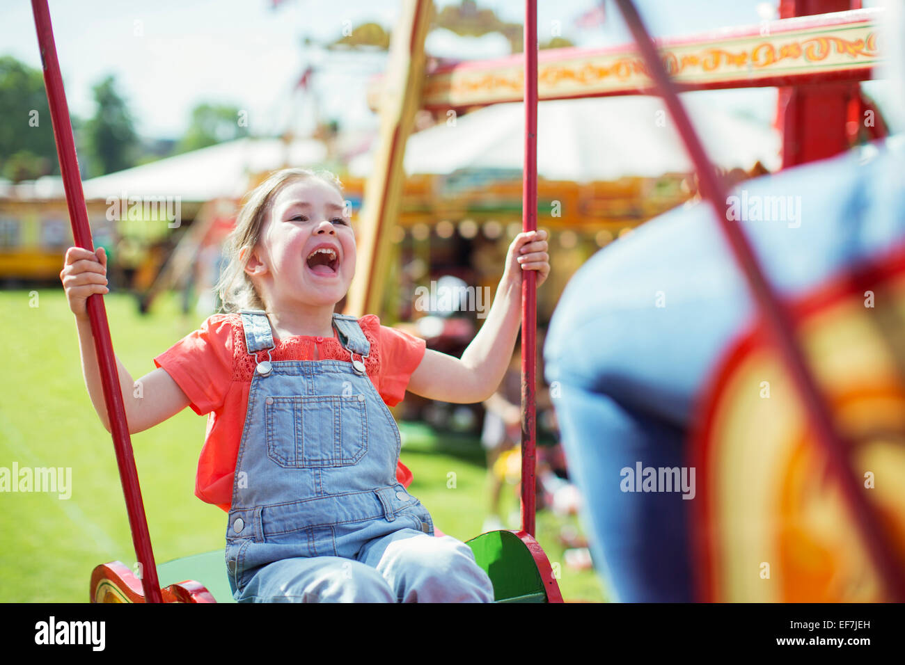 Fröhliches Mädchen lachend auf Karussell im Vergnügungspark Stockfoto