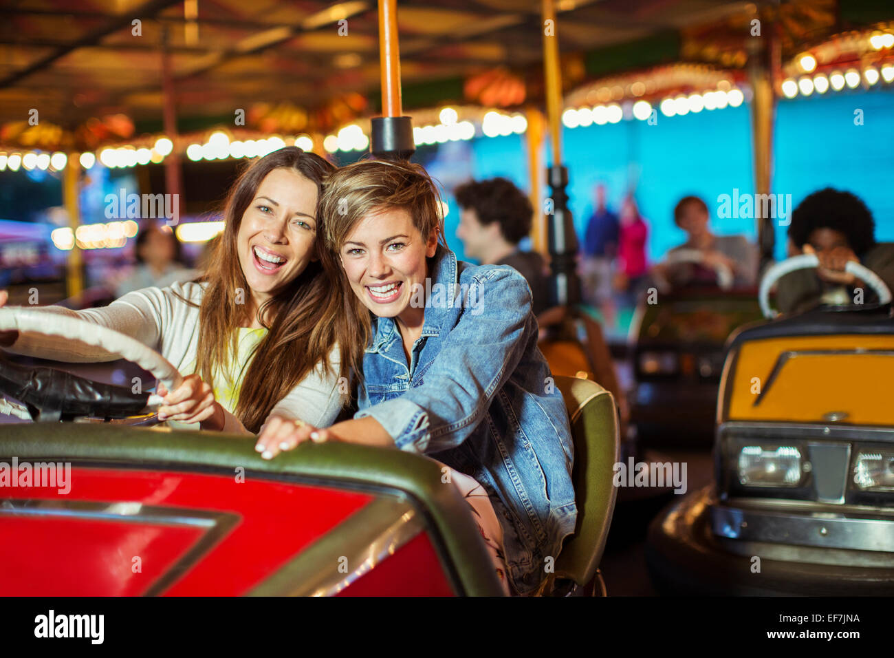 Zwei fröhliche Frauen auf Autoscooter fahren im Freizeitpark Stockfoto