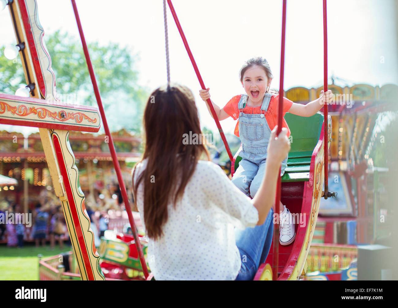 Mutter und Tochter spielen auf Schaukel im Vergnügungspark Stockfoto