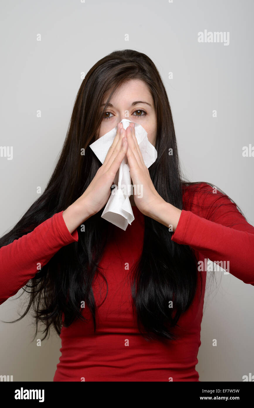 Junge Frau in roten Bluse, die ihre Nase mit Seidenpapier Stockfoto