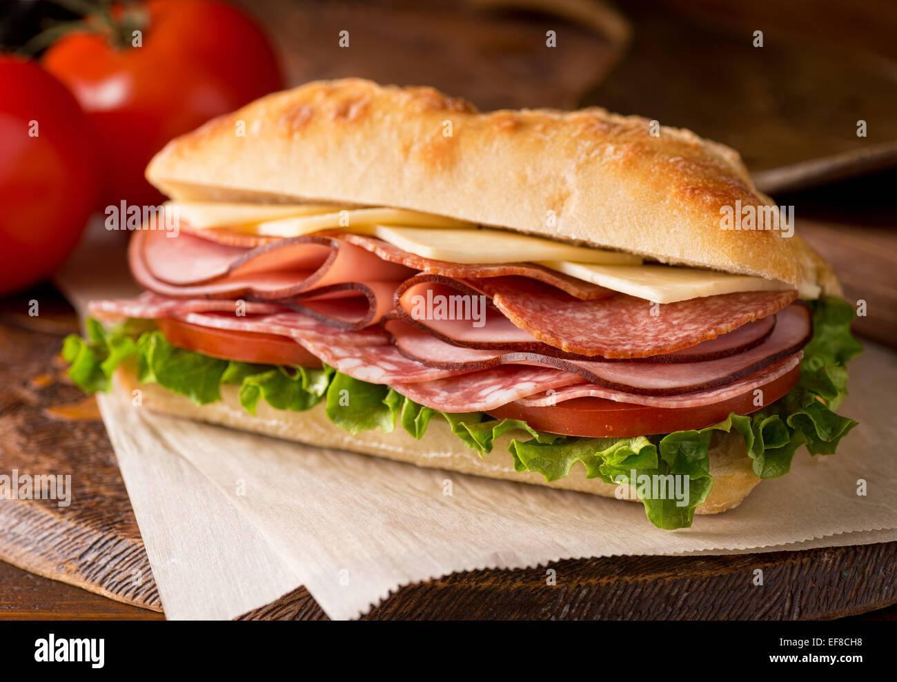 Ein leckeres Sandwich mit Aufschnitt, Salat, Tomaten und Käse auf ... Ein leckeres Sandwich mit Aufschnitt, Salat, Tomaten und Käse auf ...