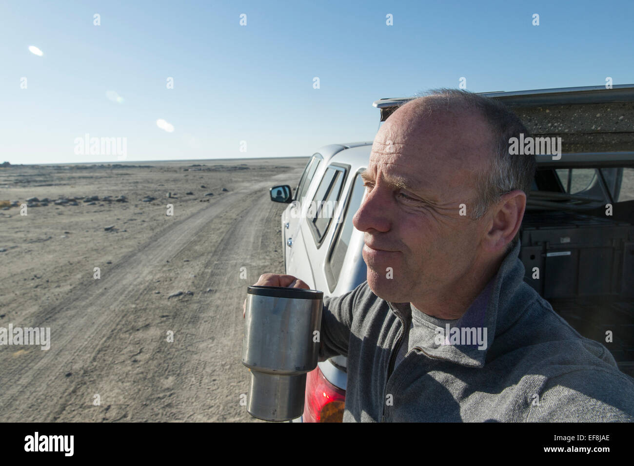 In der Nähe von Kubu Island, Afrika, Botswana, Selbstporträt des Fotografen Paul Souders nippen Morgenkaffee auf Makgadikgadi Pan. Stockfoto