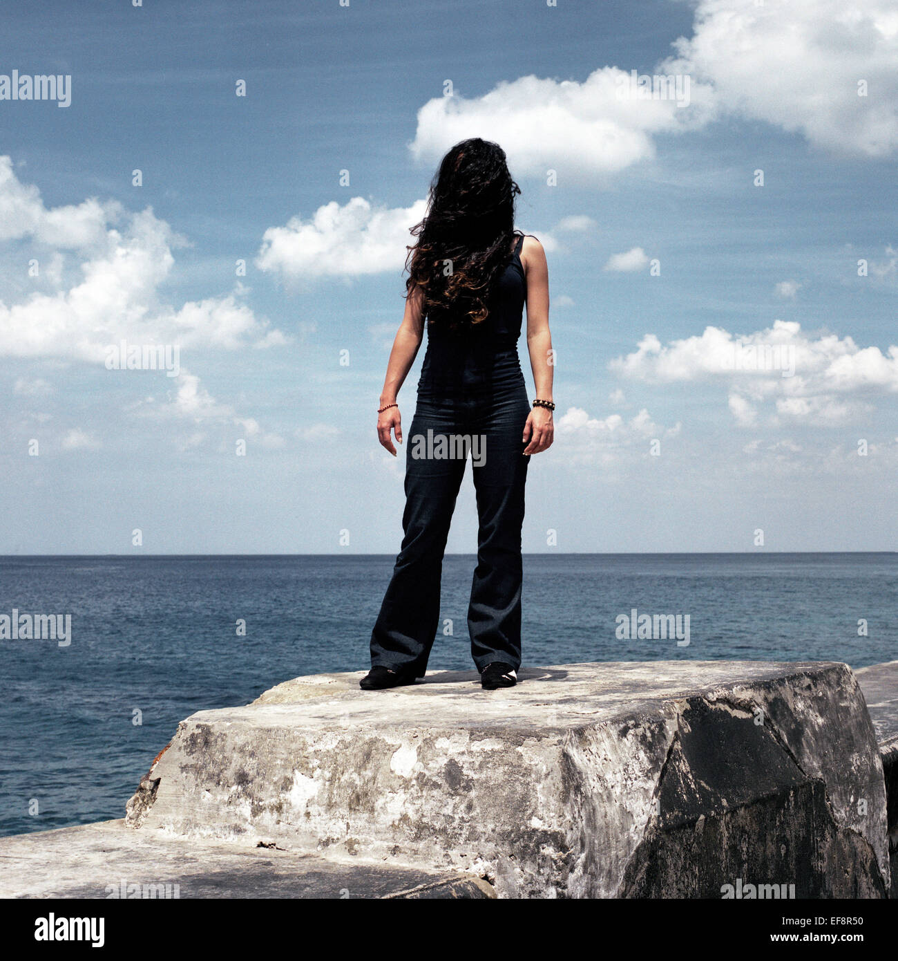 Frau mit langem Haar bedeckt Gesicht auf einer Wand am Meer, Havanna, Kuba Stockfoto