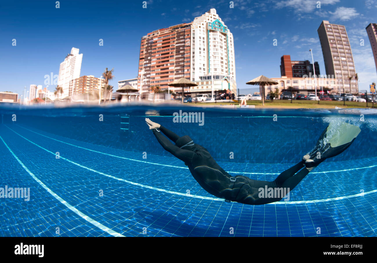 Südafrika, KwaZulu Natal, Durban, Mann mit Monoflosse Tauchen im Schwimmbad mit Strandhotels im Hintergrund Stockfoto
