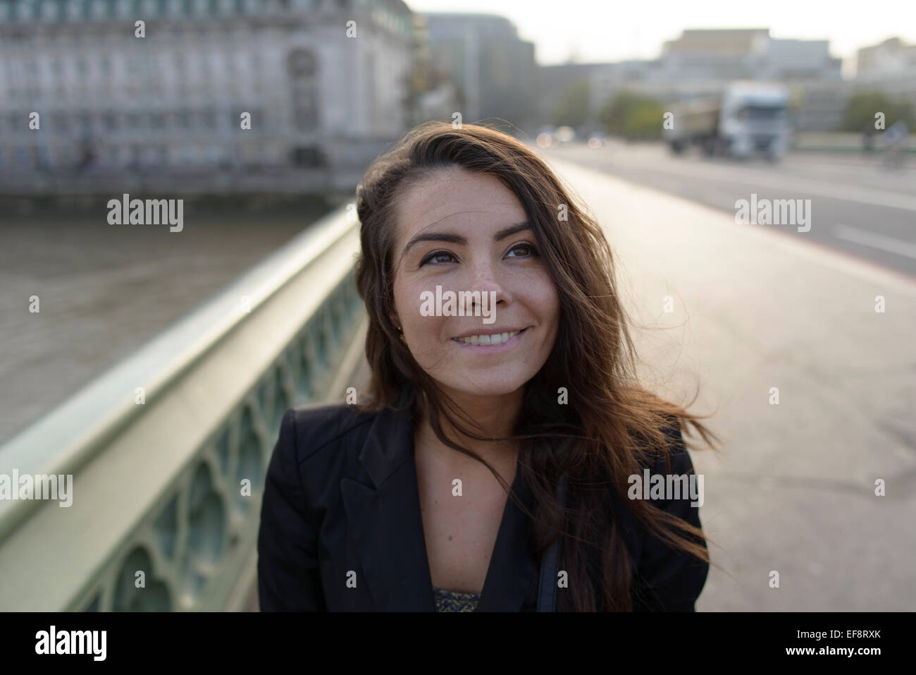 Lächelnde Frau auf der Westminster Brücke stehend, die nach oben schaut, London, England, Großbritannien Stockfoto