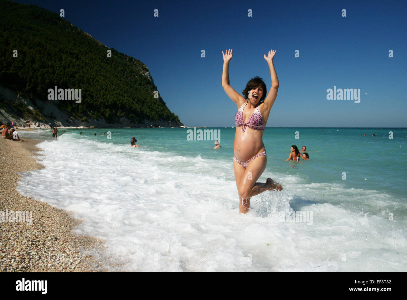 Italien, Marken, Sirolo, glückliche schwangere Frau am Strand Stockfoto