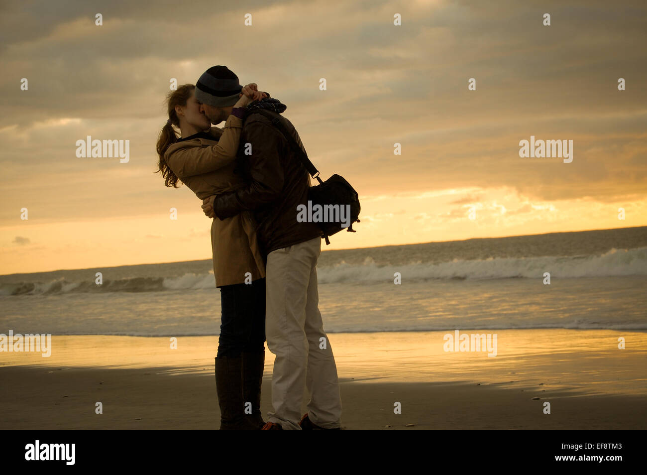 Paar zu umarmen und küssen am Strand bei Sonnenuntergang Stockfoto