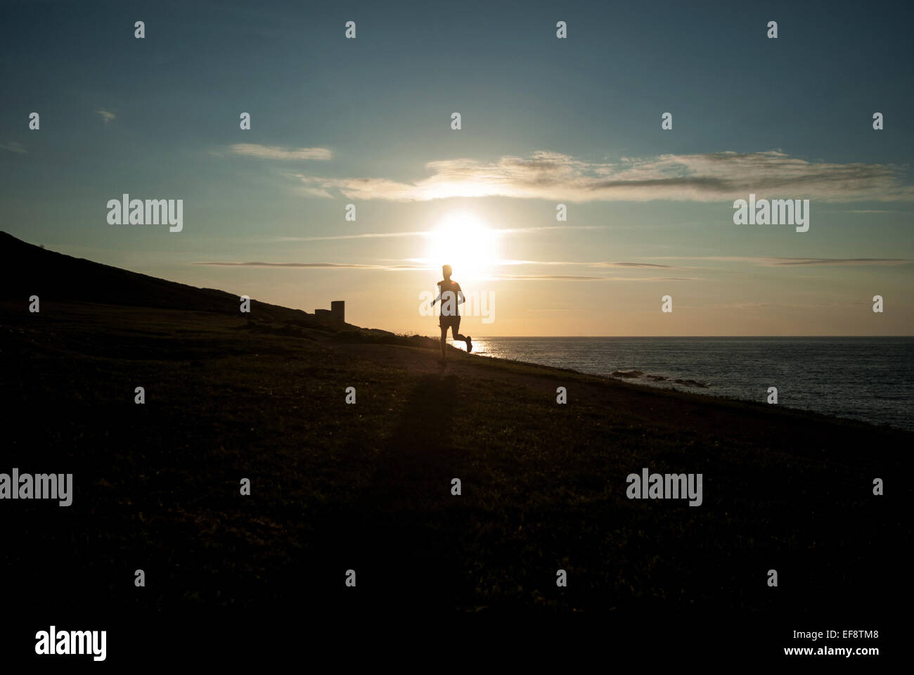 Silhouette der Mann läuft am Strand bei Sonnenuntergang, Galicien, Spanien Stockfoto