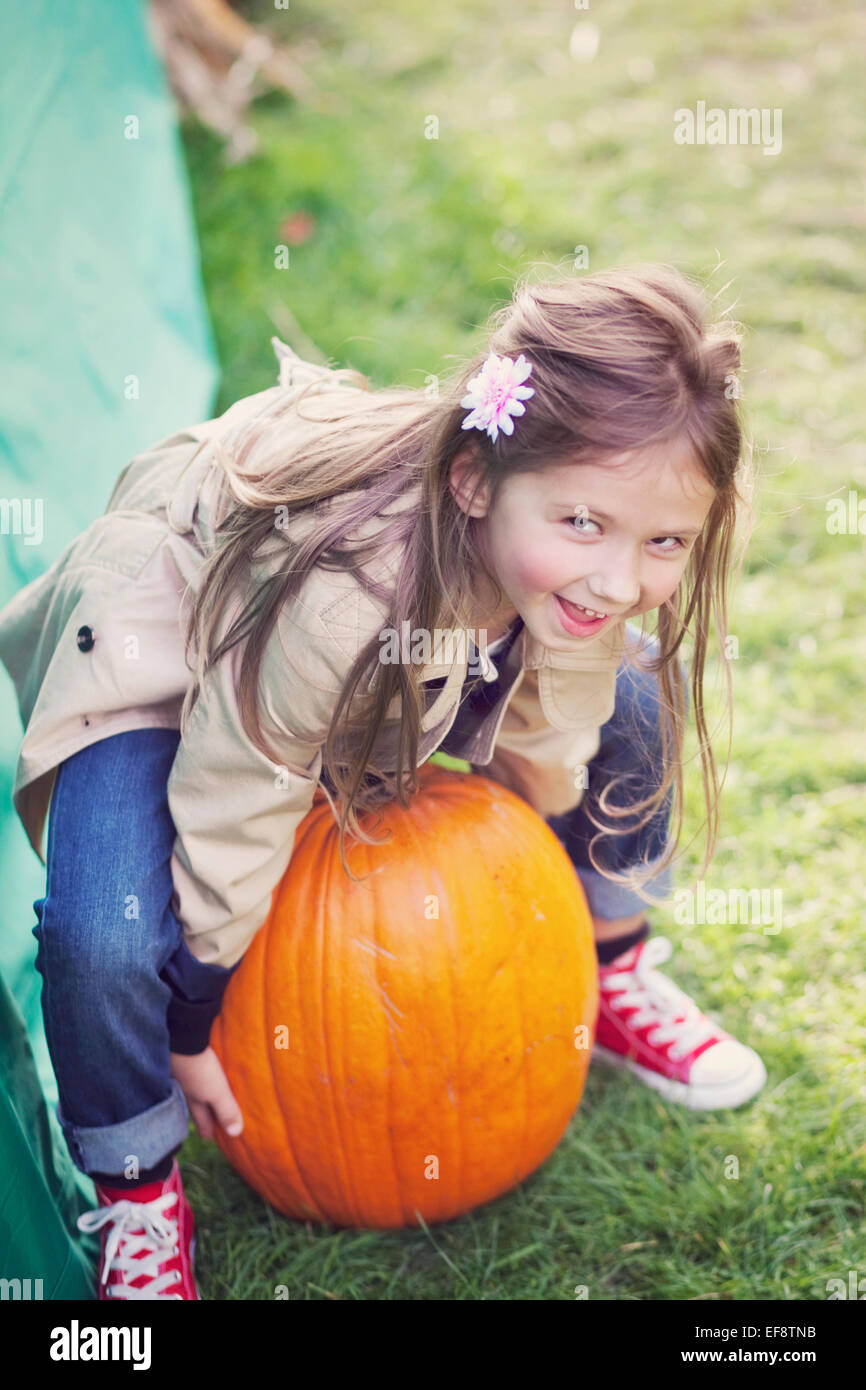 Mädchen (4-5) versucht, großen Kürbis heben Stockfoto