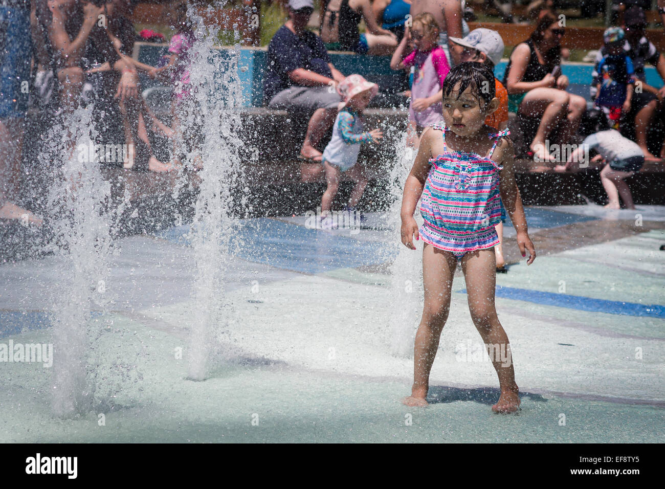 Barfuß Mädchen nähert sich Brunnen im Sommer, Menschen im Hintergrund Stockfoto