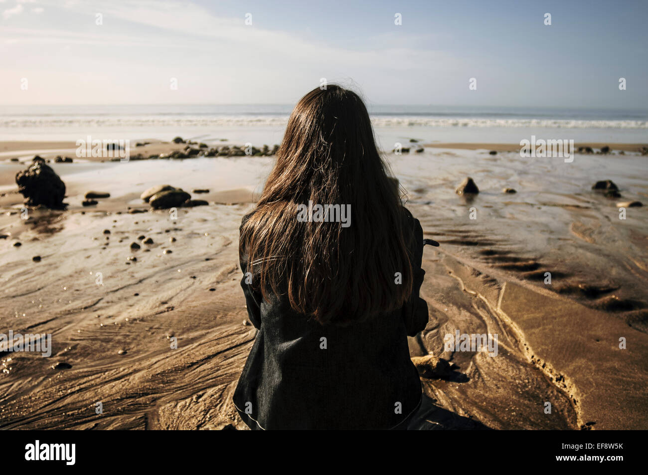 Rückansicht einer Frau, die am Strand sitzt und die Aussicht betrachtet, Deauville, Lisieux, Calvados, Basse-Normandie, Frankreich Stockfoto