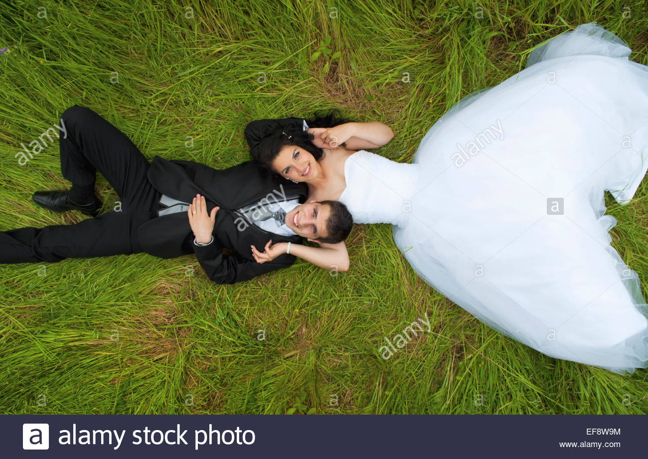 Braut und Bräutigam auf dem Rasen liegend Stockfoto