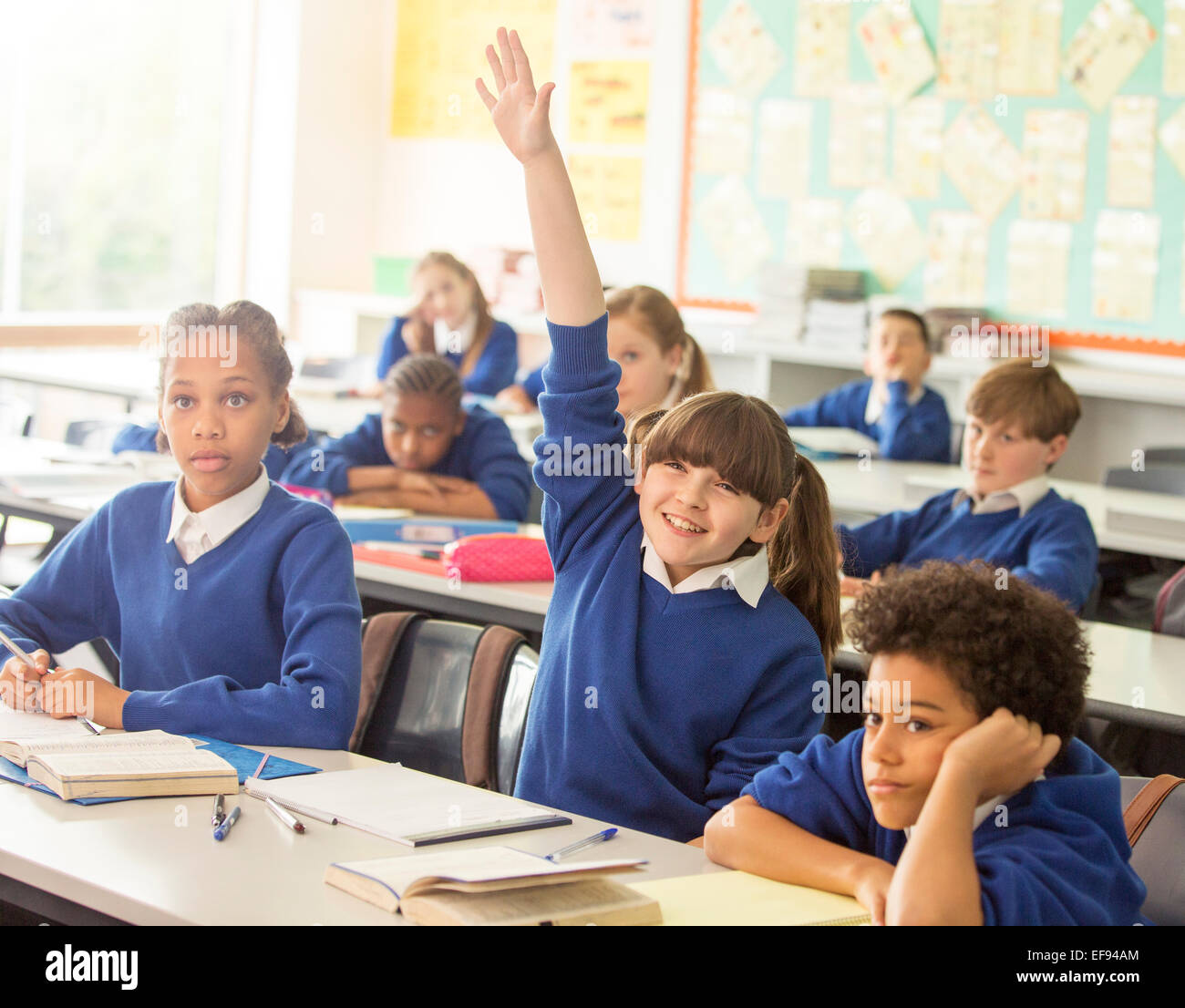 Grundschulkinder im Klassenzimmer während der Lektion, lächelndes Mädchen Hand heben Stockfoto