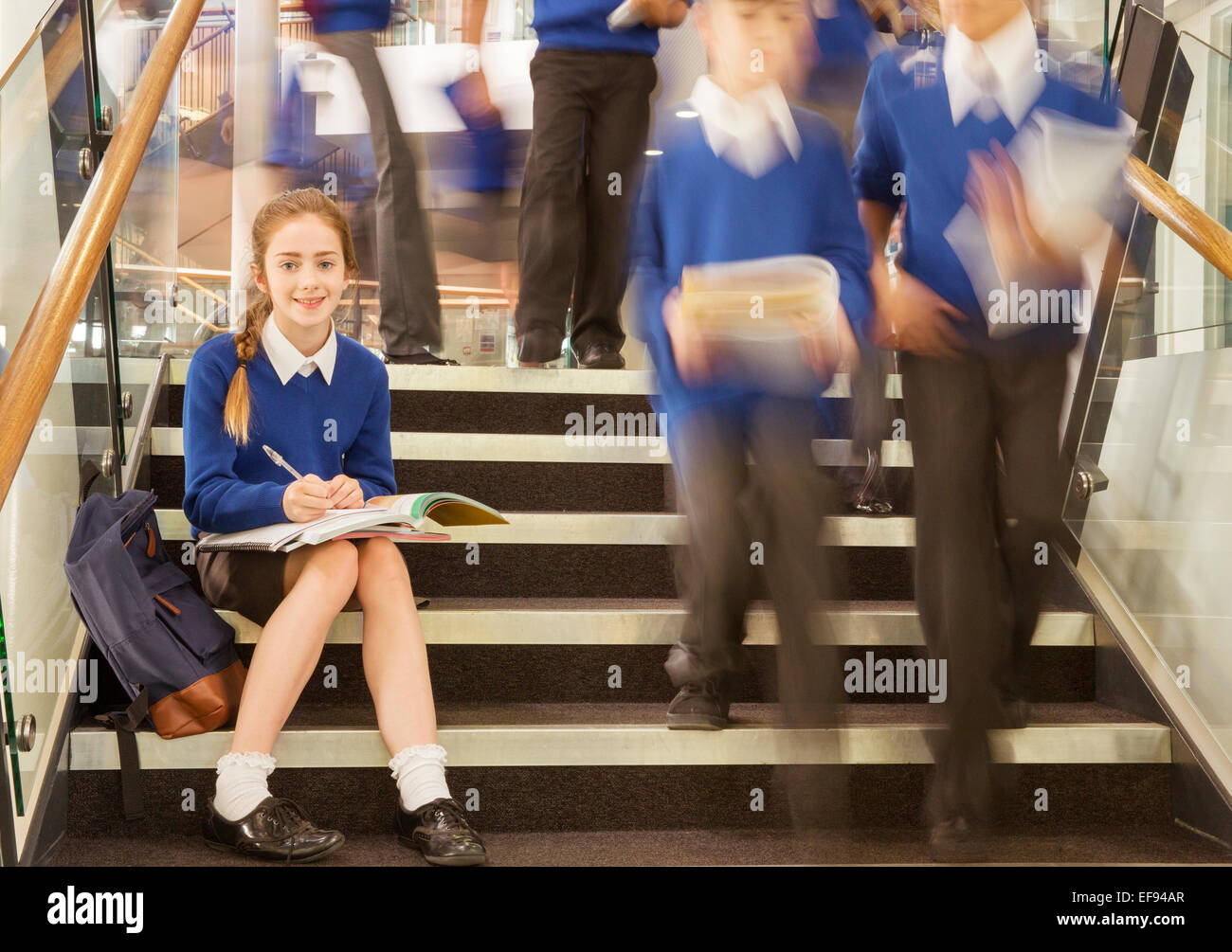 Porträt des Lächelns Grundschule Mädchen sitzen auf Schritte in der Schule Stockfoto