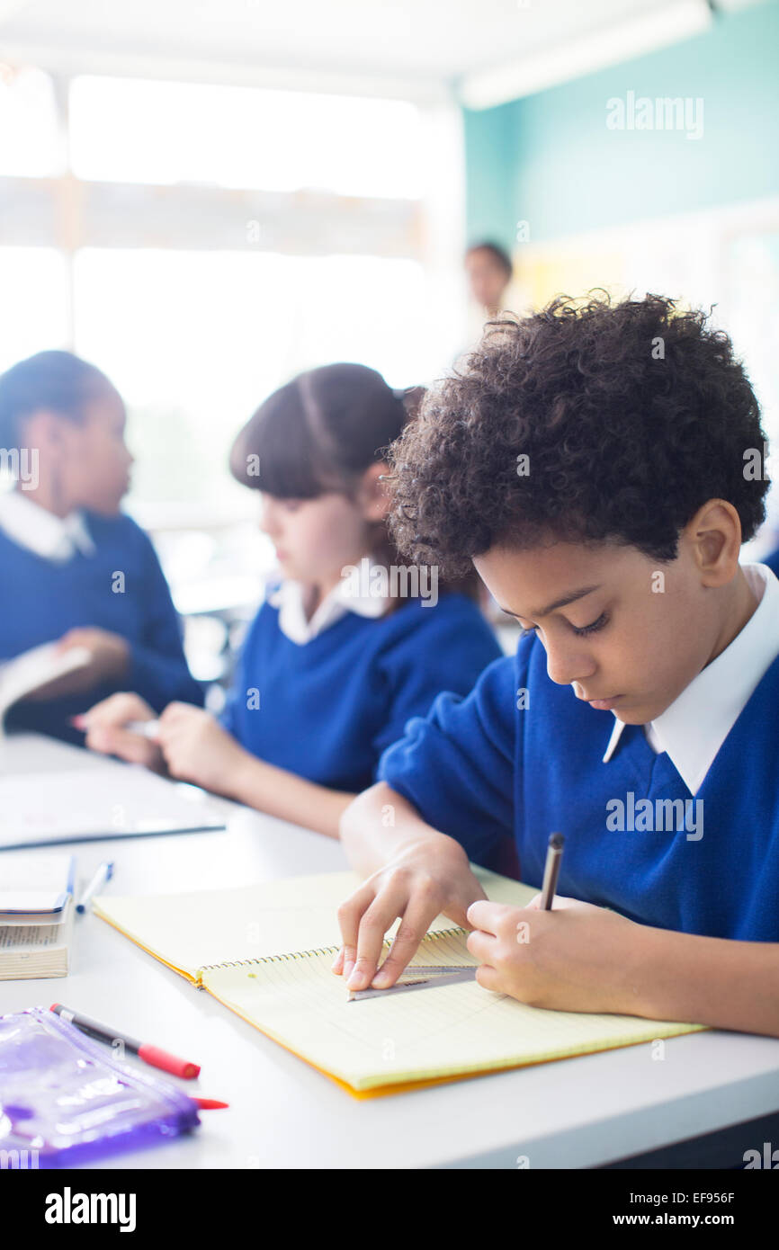 Schüler zeichnen im Notebook am Schreibtisch im Klassenzimmer, Mädchen im Hintergrund Stockfoto