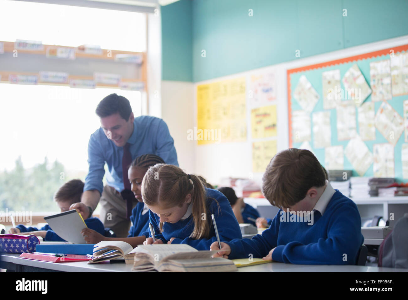 Männliche Lehrer unterstützen Grundschulkinder im Klassenzimmer während der Lektion Stockfoto