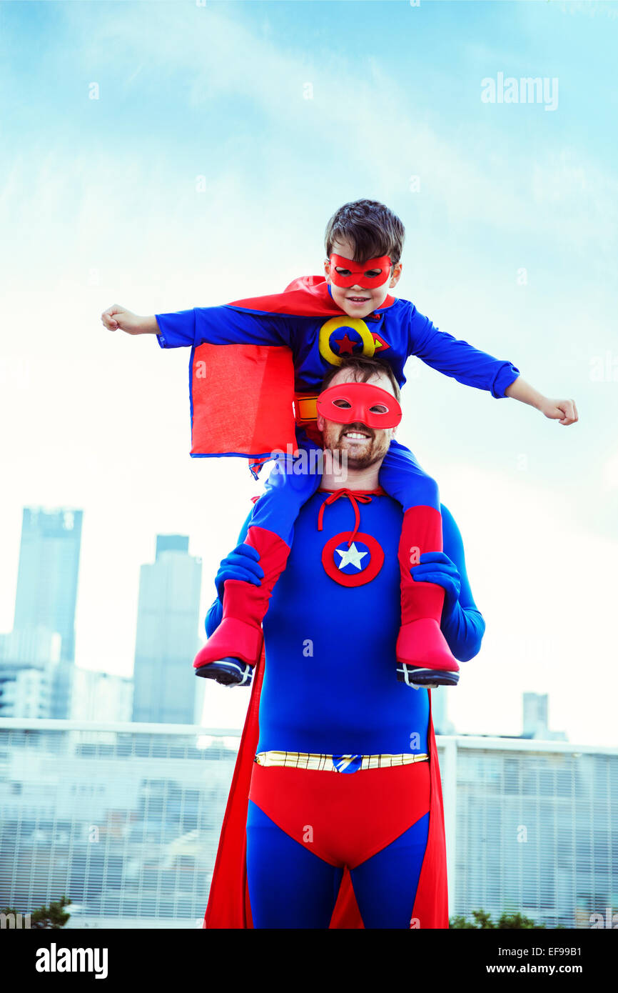 Superhelden-Vater mit Sohn auf Schultern auf Stadt auf dem Dach Stockfoto