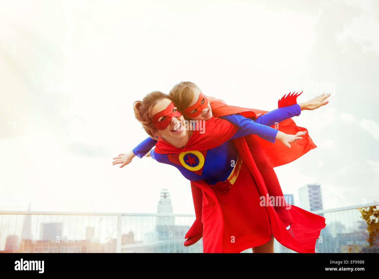 Superhelden-Mutter und Tochter spielen auf Stadt auf dem Dach Stockfoto