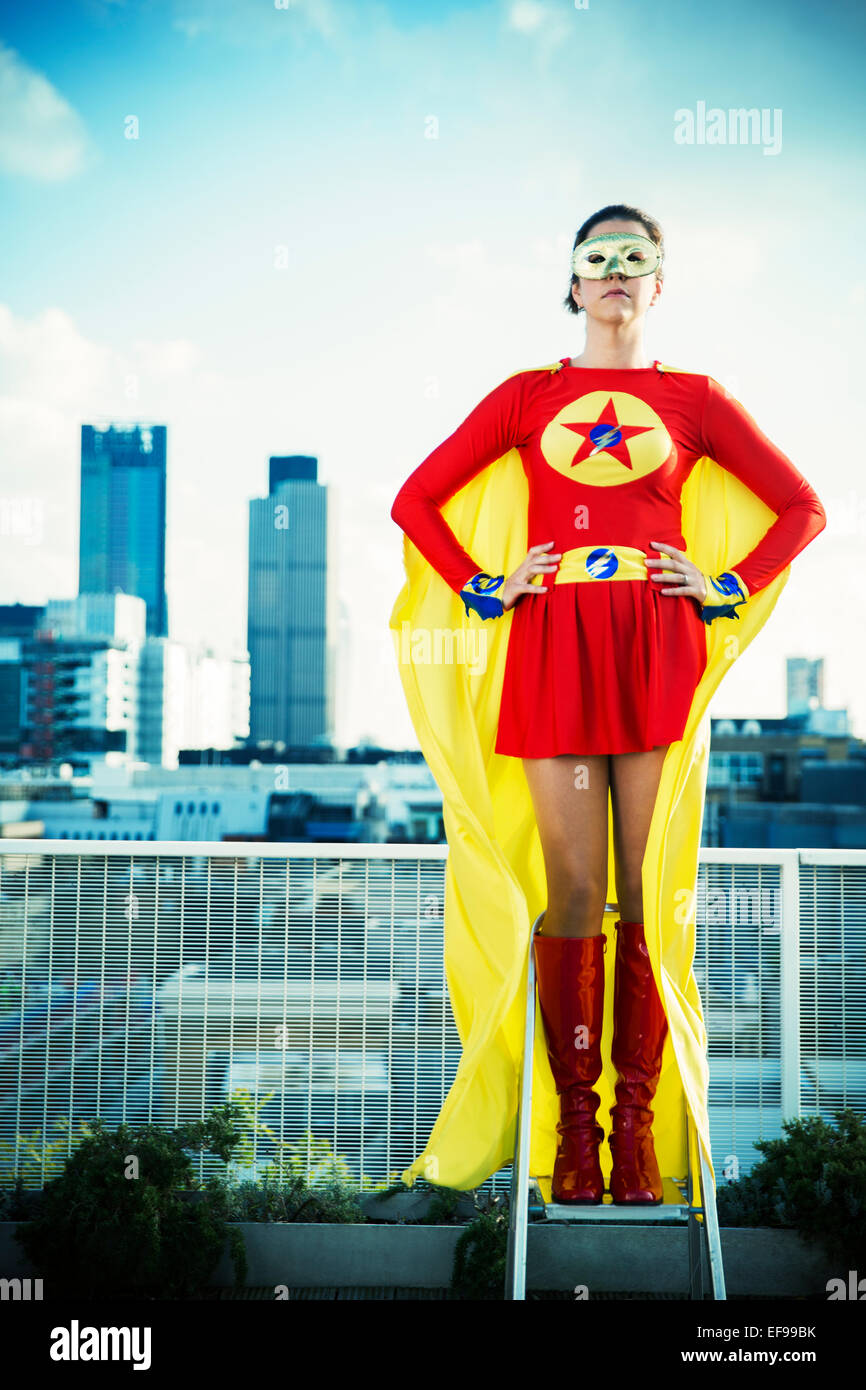 Superheld stehend auf Trittleiter auf Stadt auf dem Dach Stockfoto
