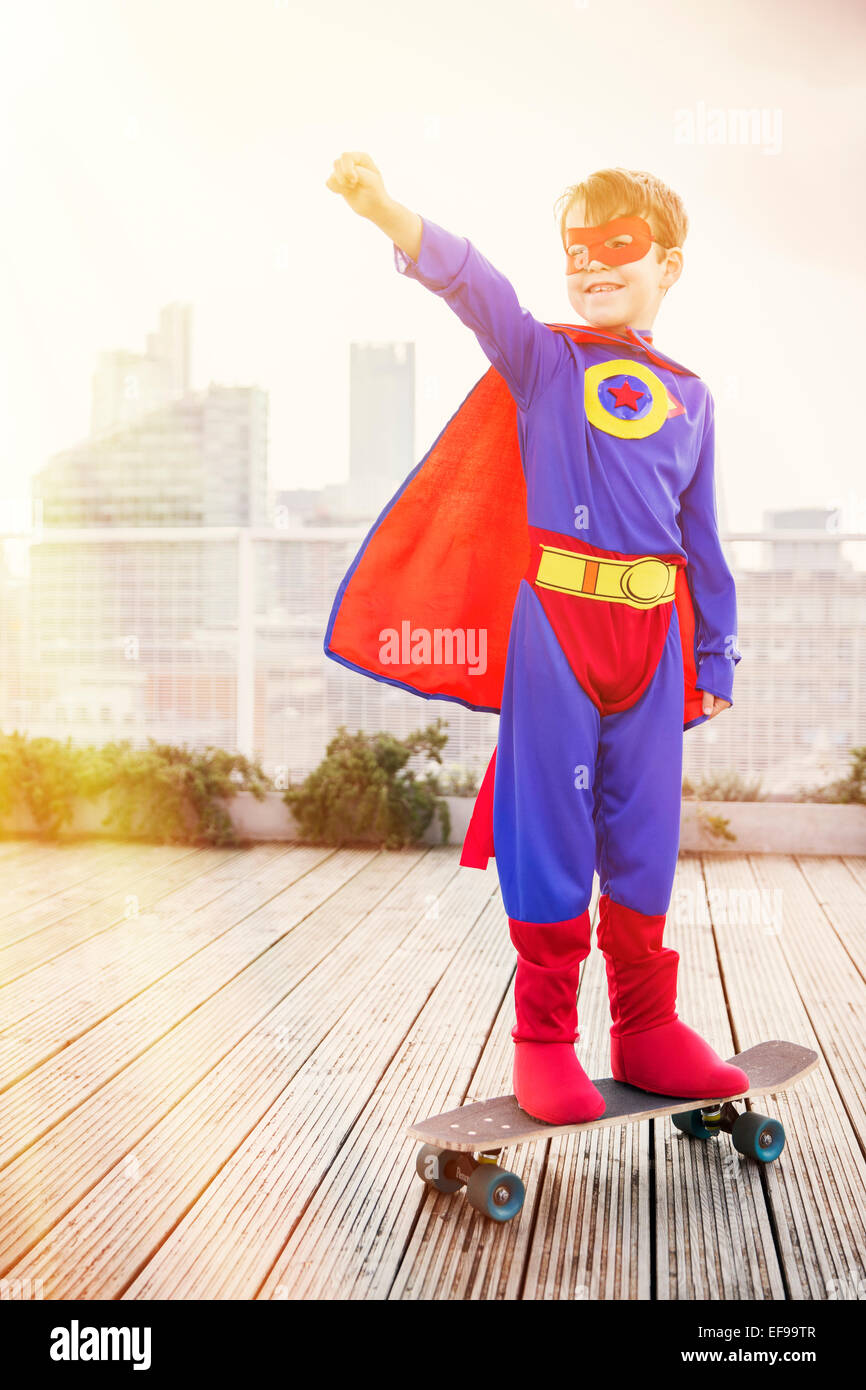 Superheld Junge stand auf Skateboard auf Stadt auf dem Dach Stockfoto