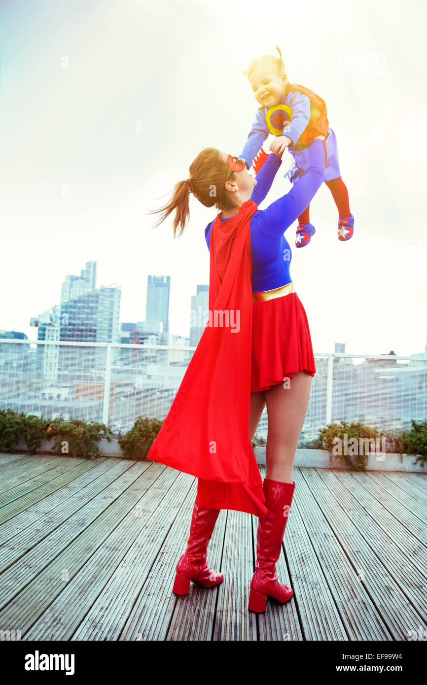 Superhelden-Mutter mit Tochter auf Stadt auf dem Dach spielen Stockfoto