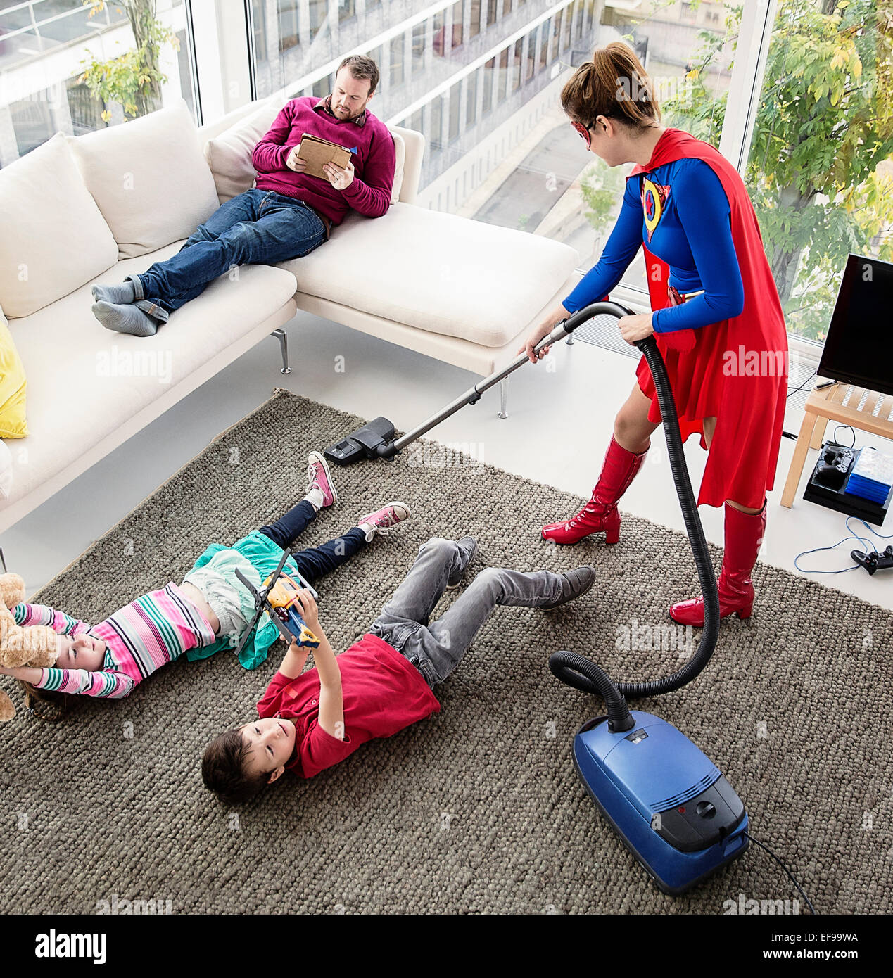 Superhelden-Familie im Wohnzimmer Staubsaugen Stockfoto