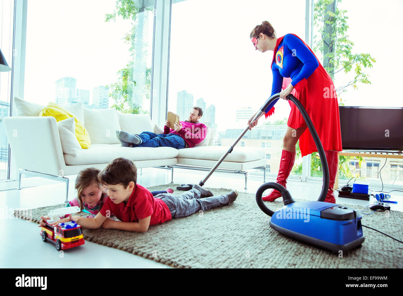 Superhelden-Familie im Wohnzimmer Staubsaugen Stockfoto