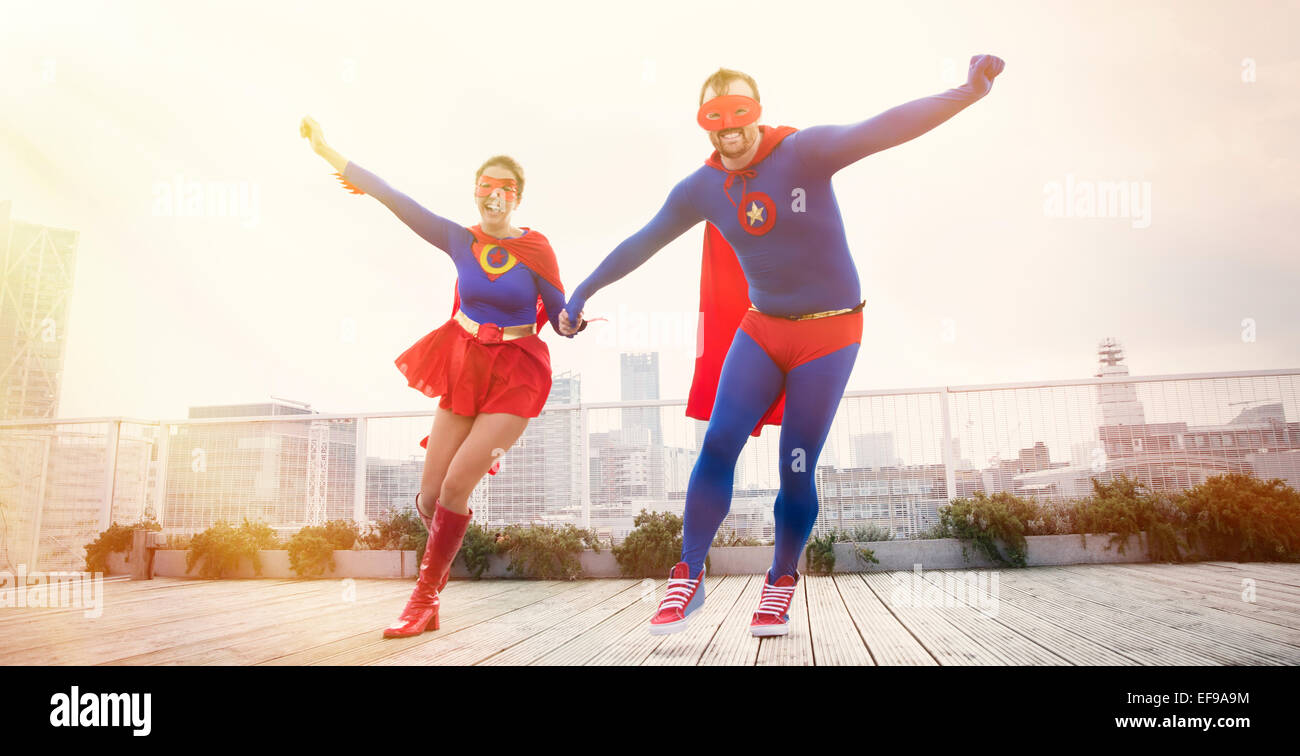 Superhelden, die Hand in Hand laufen auf Stadt auf dem Dach Stockfoto