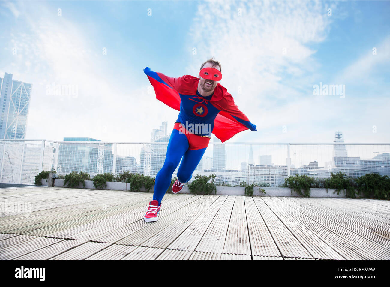 Superheld mit Umhang auf Stadt auf dem Dach ausgeführt Stockfoto