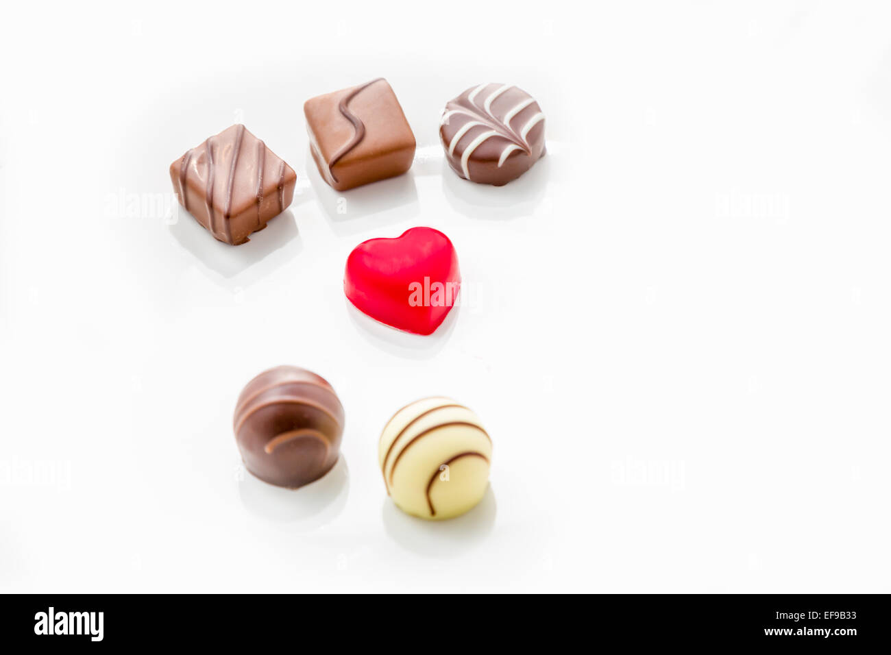 Rotes Herz geformt Schokolade auf einem weißen Teller mit Praline Schokolade oben und unten Stockfoto