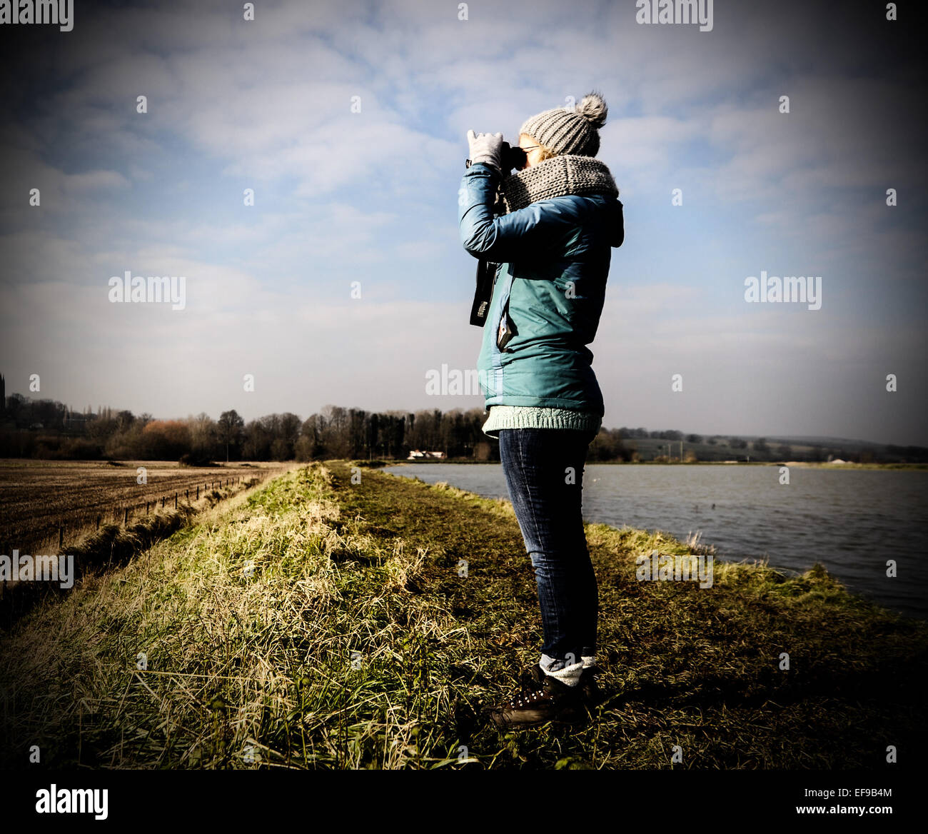 Frau Vogelbeobachtung mit dem Fernglas am Ufer des Fluss Adur in Shoreham UK Stockfoto