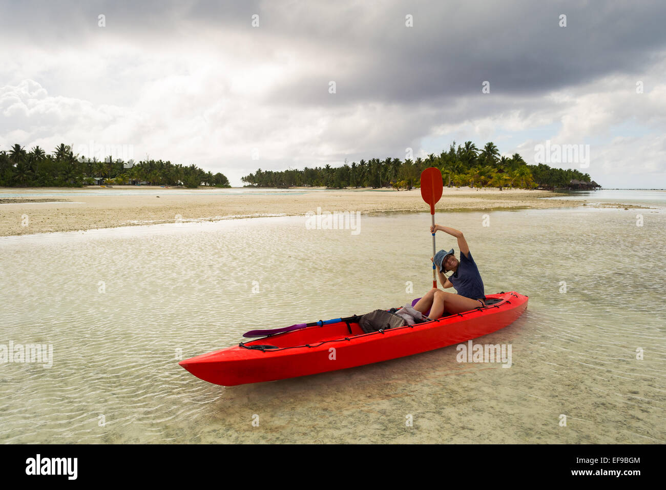 Die wunderschöne Lagune von Aitutaki per Kanu zu erkunden. Tropischer Sturm am Horizont. Frau Umgang mit Paddel. Cook-Inseln. Stockfoto