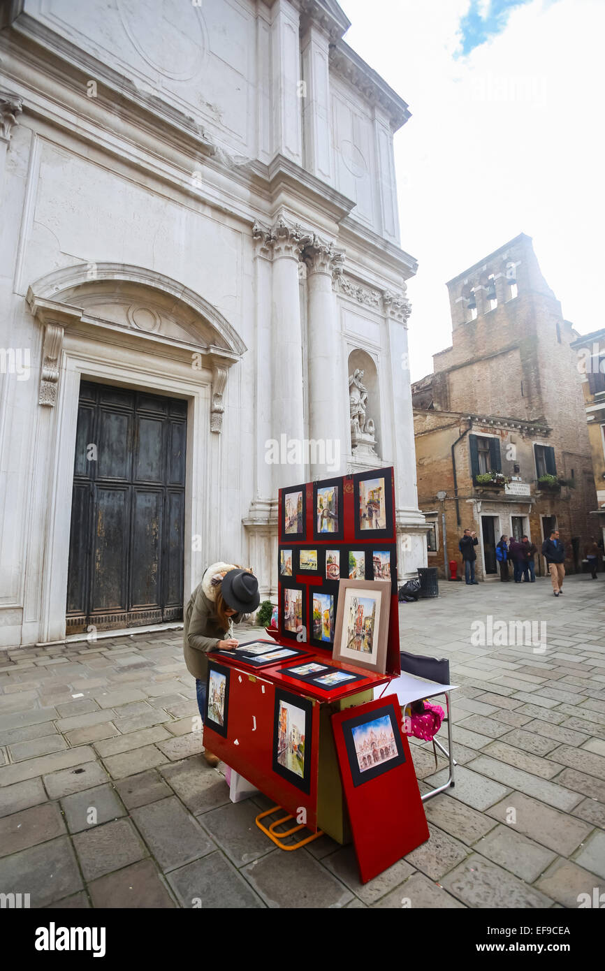 Eine Frau verkauft Kunst Bilder an einem Stand auf der Straße in Venedig, Italien. Stockfoto