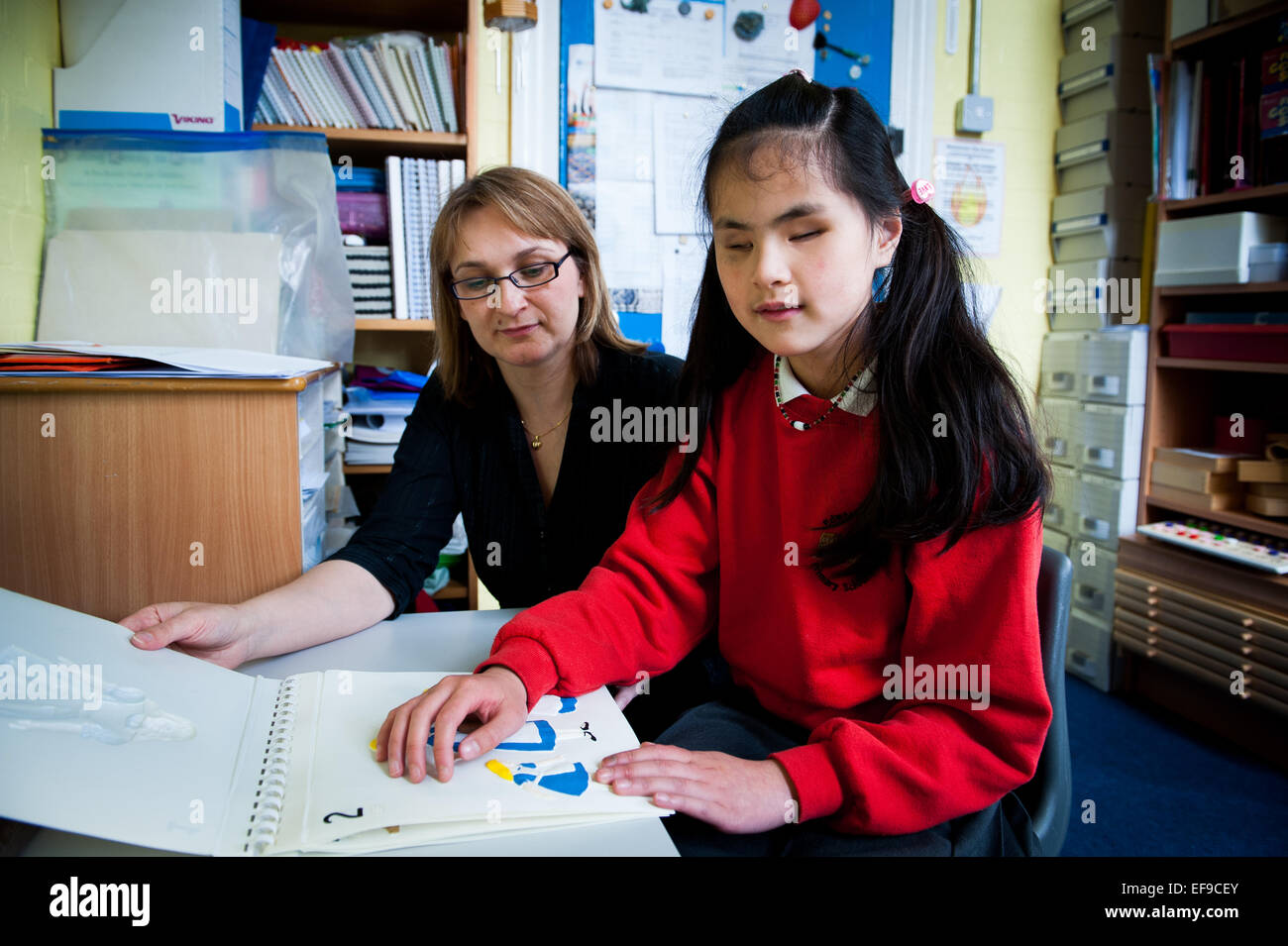 Blindes Mädchen mit Lehrer in Special Needs-Klasse in London Grundschule Stockfoto