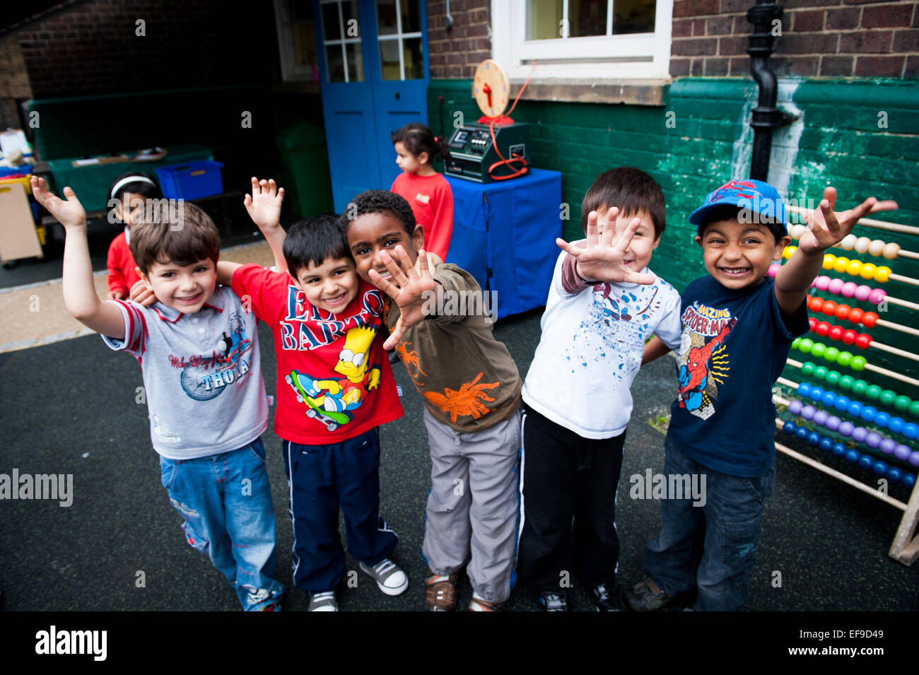 Glücklich spielenden Kinder Lächeln und winken auf dem Spielplatz der Grundschule in London W2 Stockfoto