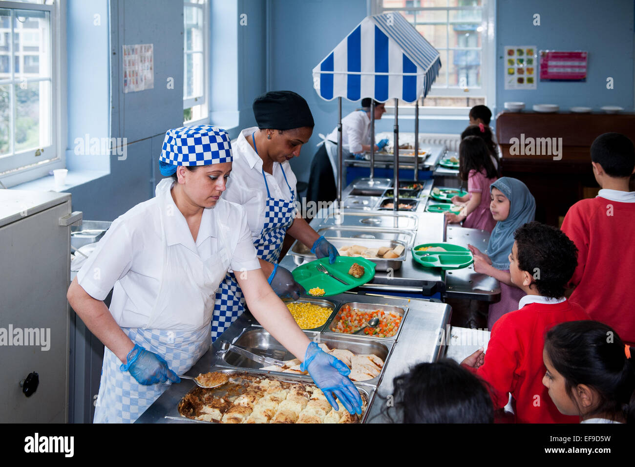 Mittagessen in der UK State Primary School Dinner Damen servieren Grundschulkinder gesundes Essen in der Primary School, London Stockfoto
