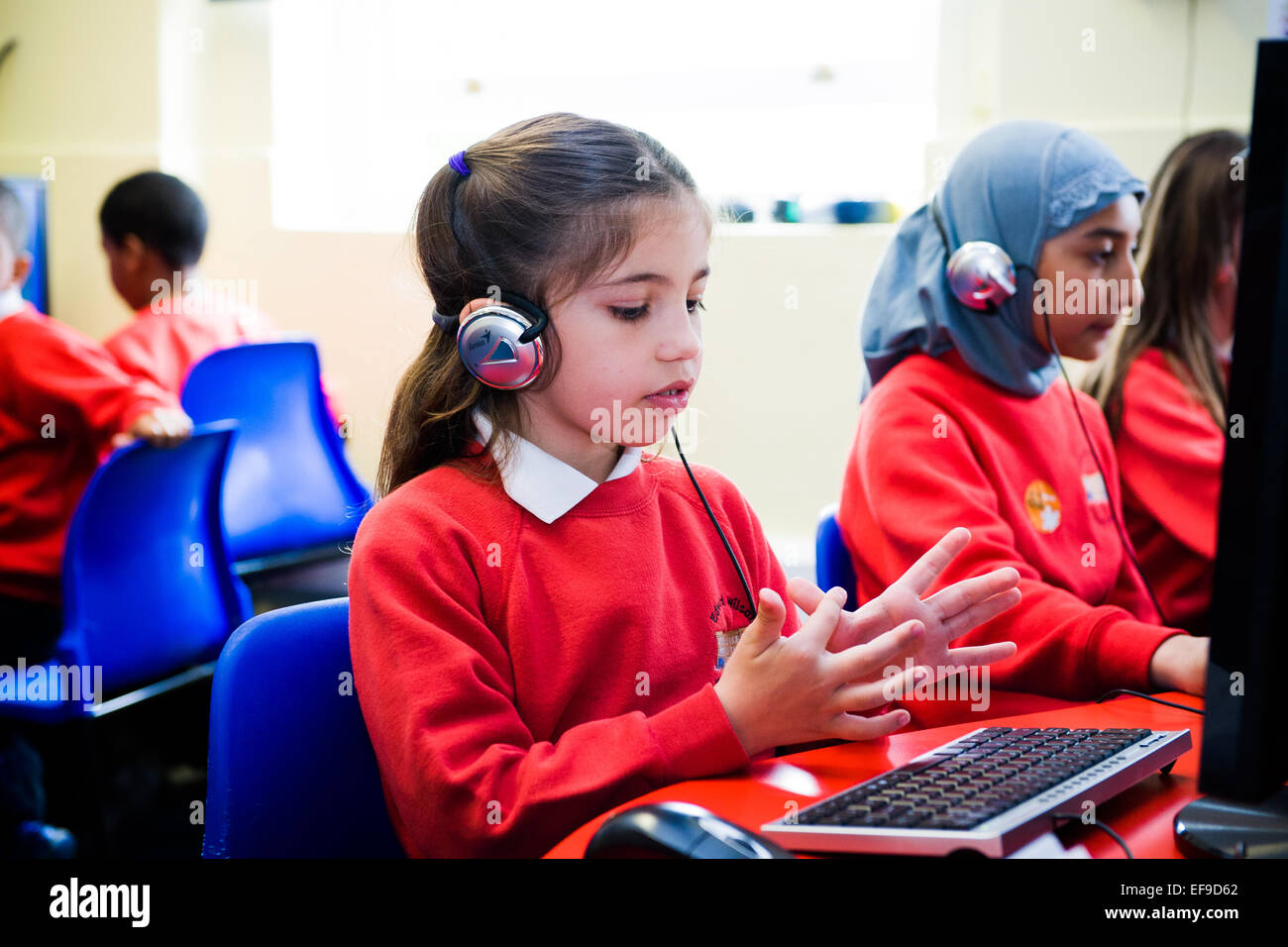 Mädchen in der Grundschule eine Online-Mathe-Klausur zu tun und mit ihren Fingern zählen Stockfoto