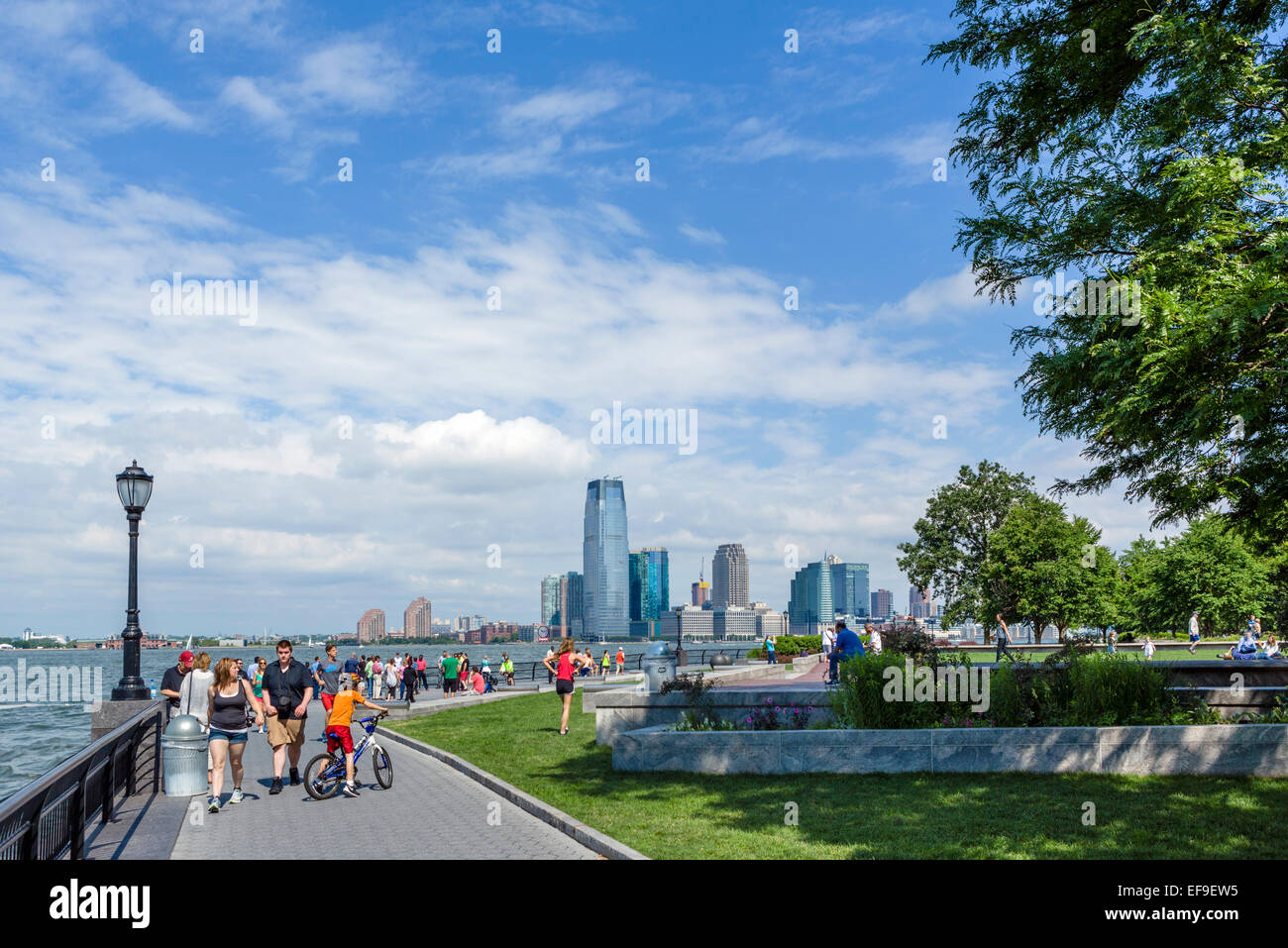 Die Esplanade in Robert F Wagner Park mit Jersey City Skyline hinter Battery Park City, Lower Manhattan, New York City, NY, USA Stockfoto