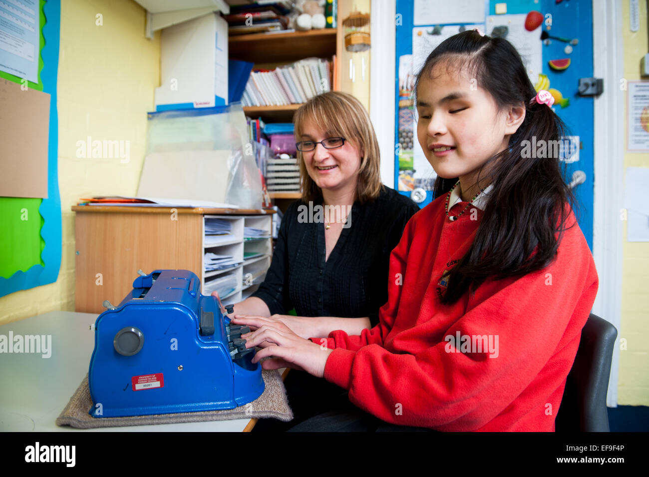 Blindes Mädchen mit Lehrer und Braille-Schreibmaschine in Special Needs-Klasse in London Grundschule Stockfoto