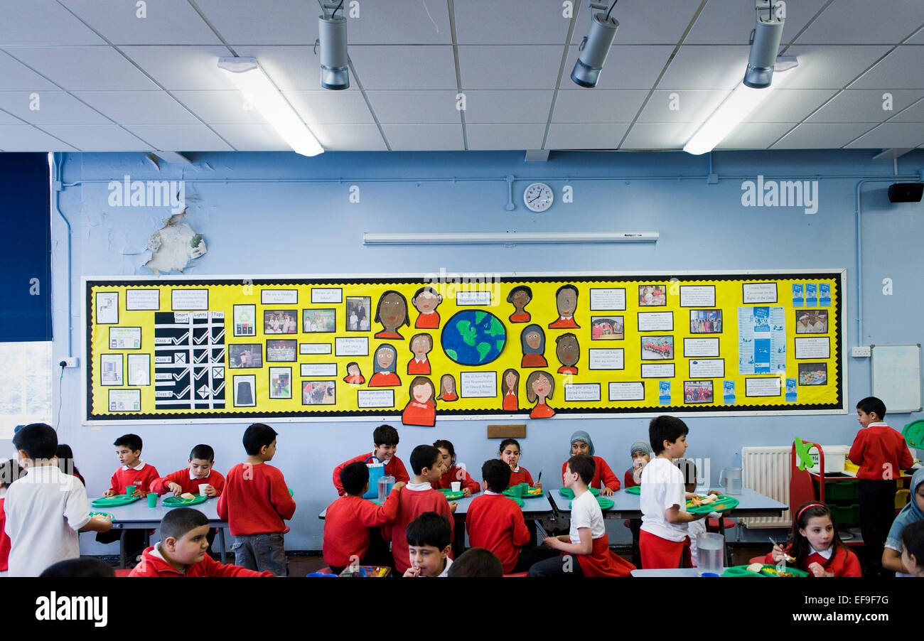 Zur Mittagszeit am UK staatliche Grundschullehrer und Kinder im Grundschulalter in der Grundschule Stockfoto