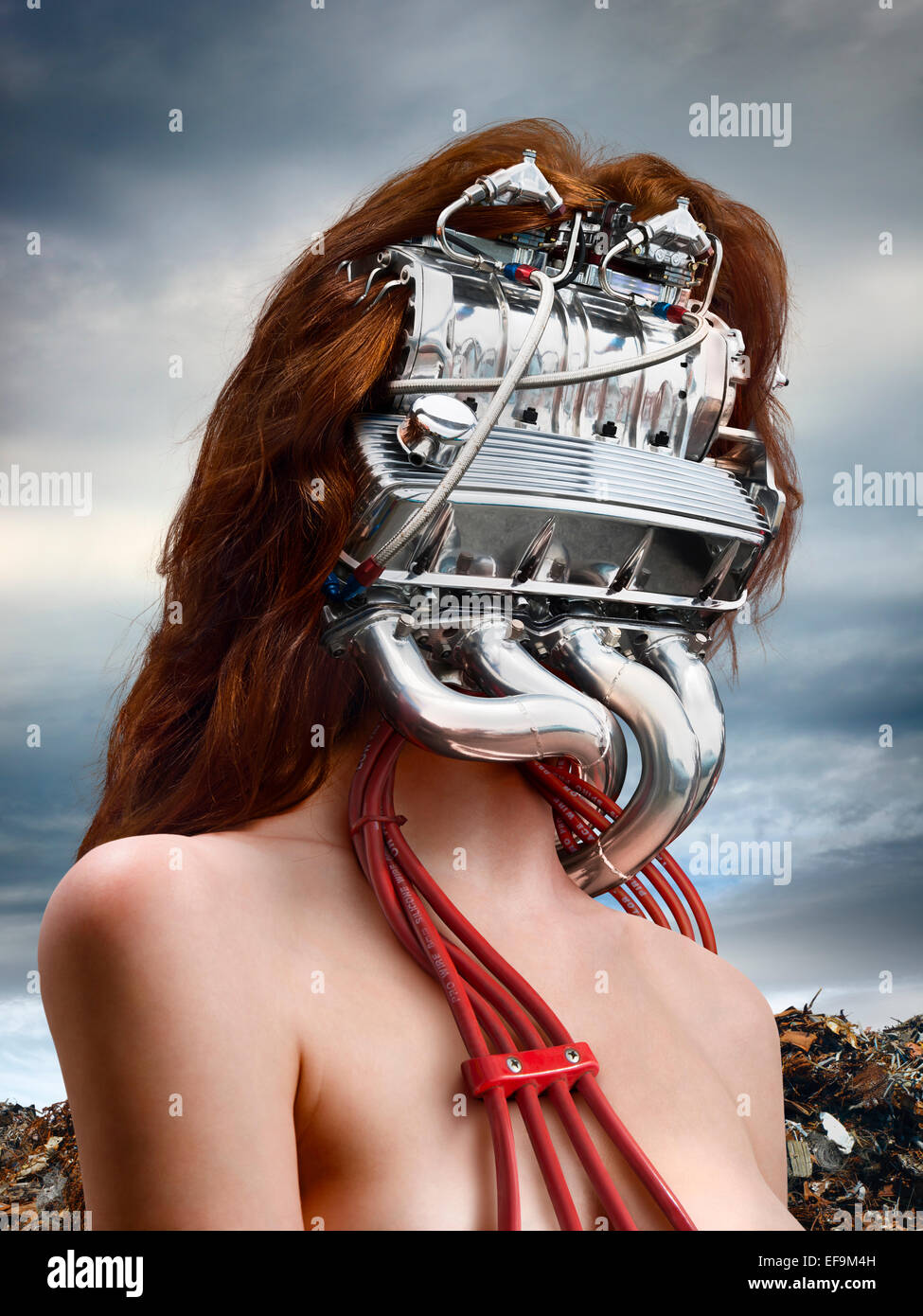 Vertikale Fantasy Bild der Frau mit einem Automotor für einen Kopf mit einem Schrottplatz hinter ihr Stockfoto